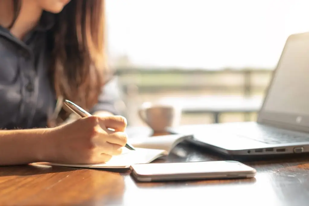Woman using a laptop and notepad to build organization skills for adult ADHD
